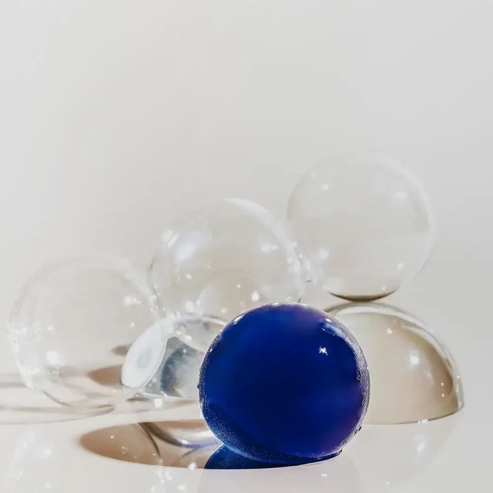 Blauer Ball und transparente Kugeln. Auf weißer Oberfläche.