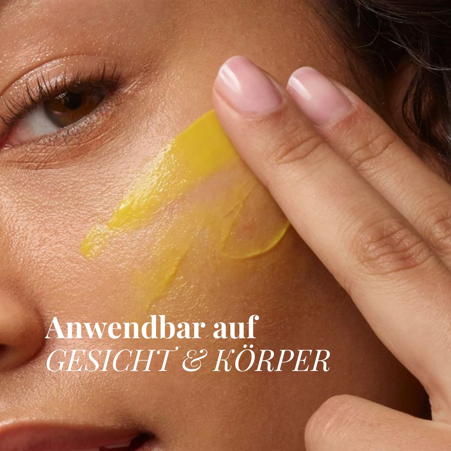 Finger tragen gelbe Salbe auf das Gesicht einer Frau auf. "Anwendbar auf Gesicht & Körper."