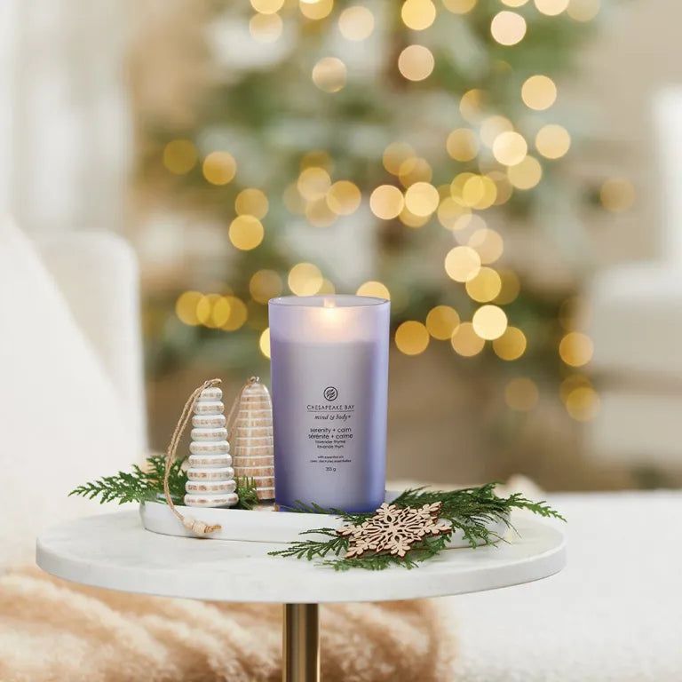 Brennende Kerze in blauem Glas. Aufschrift: Chesapeake Bay, mind & body, serenity + calm. Dekoration: Tablett, Tannenzweige, Holzornamente.