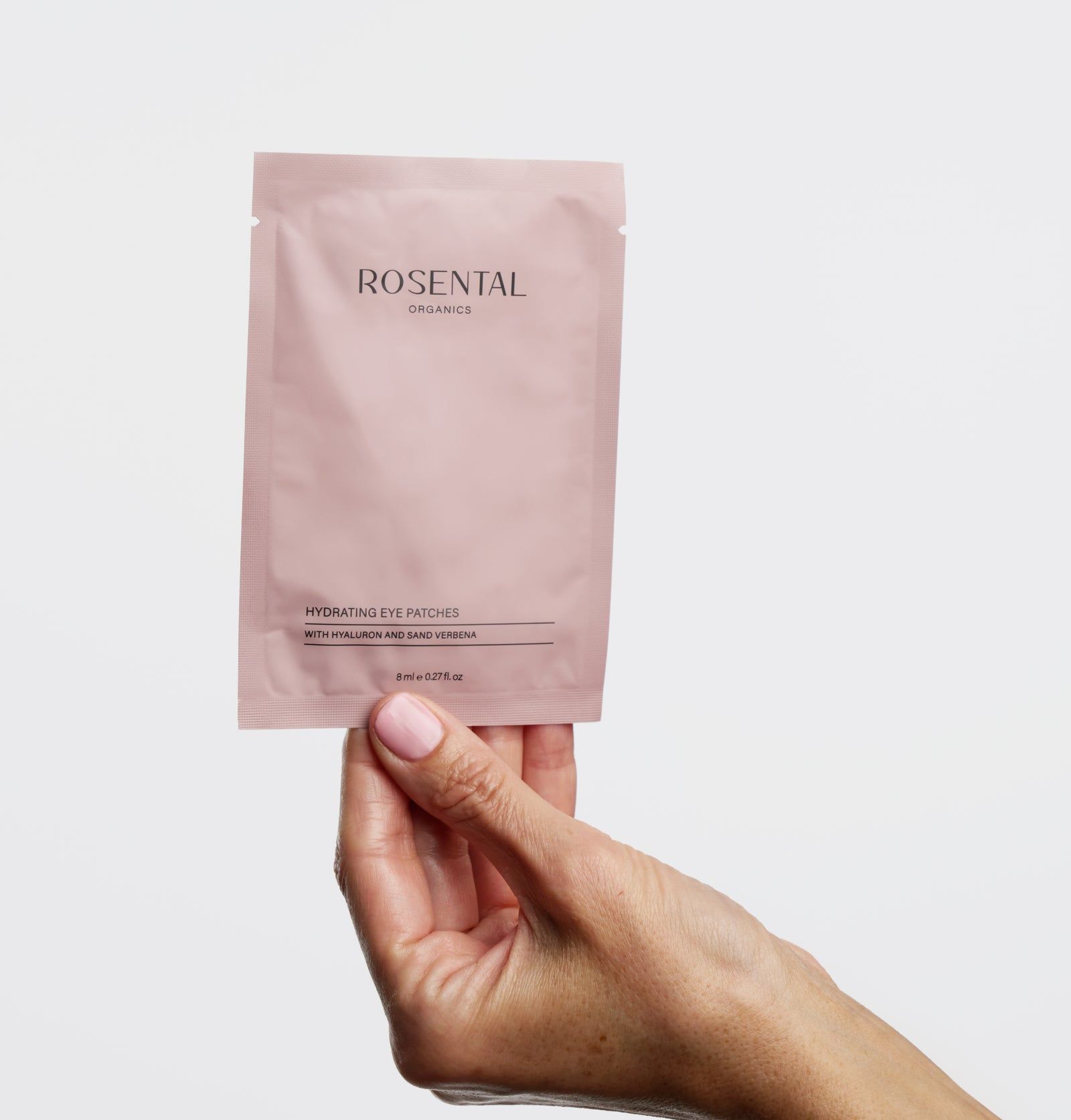 Rosa Verpackung mit Text: ROSENTAL ORGANICS, Hydrating Eye Patches. Hand hält die Verpackung.
