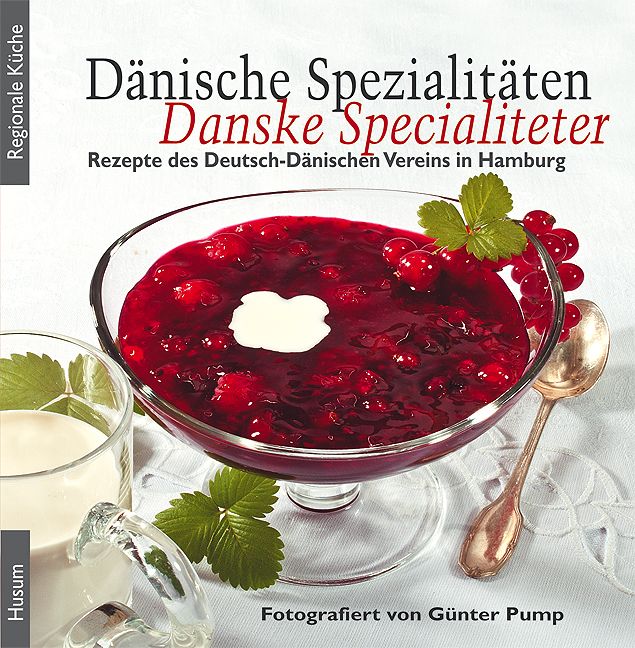 Buchcover: Dänische Spezialitäten. Rote Grütze in Glasschale, daneben Milchglas und Löffel. Text: Danske Specialiteter, Rezepte des Deutsch-Dänischen Vereins.