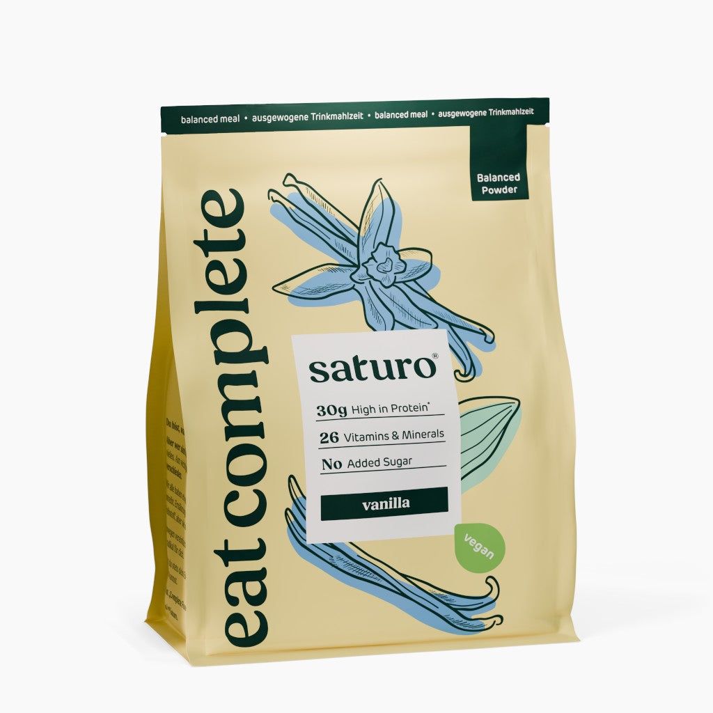 Beutel mit Vanille-Trinknahrung. Aufschrift: saturo, 30g Protein, 26 Vitamine & Mineralien, ohne Zuckerzusatz, vegan. Abbildung einer Vanilleblüte.