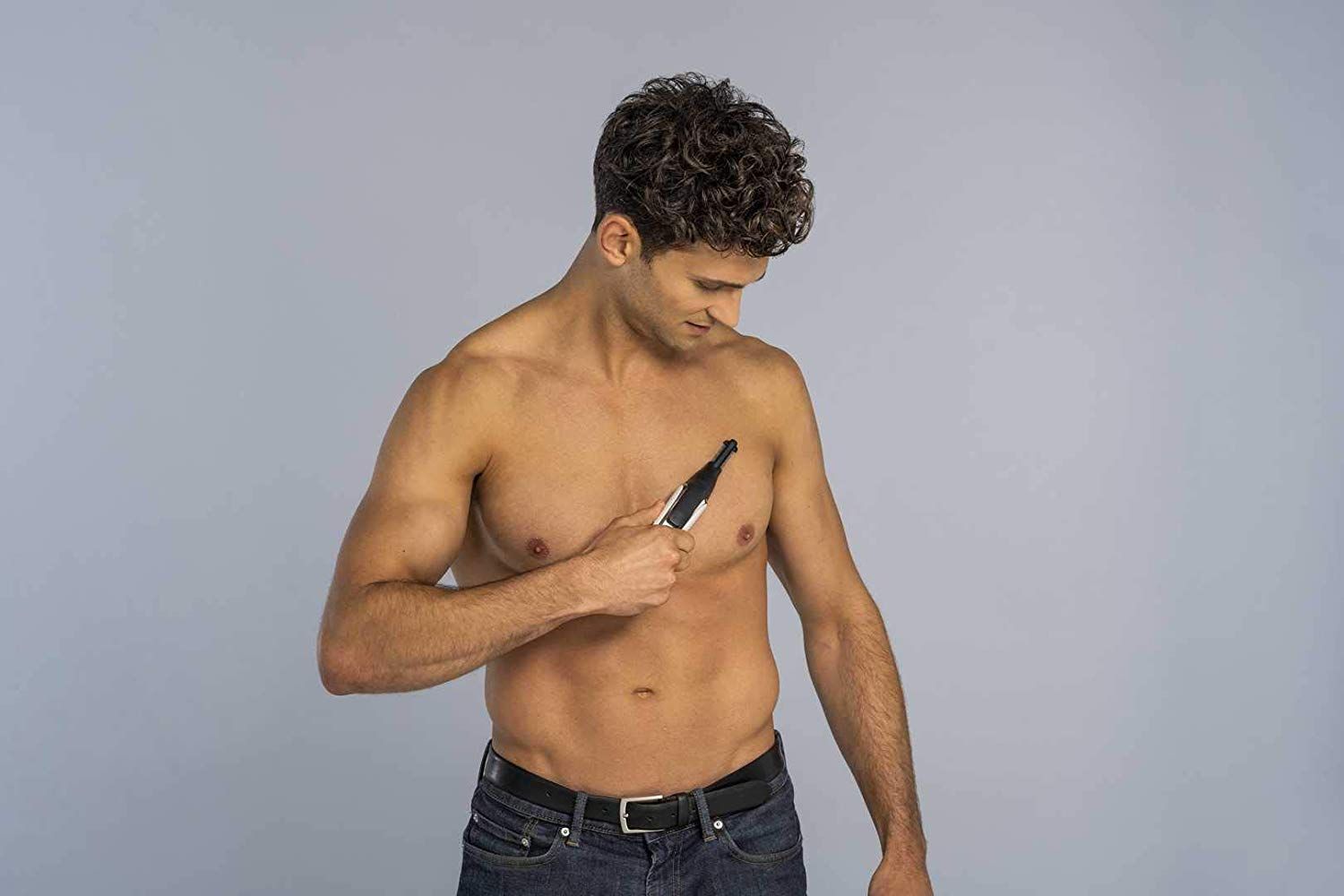 Mann rasiert sich mit einem Haarschneider. Der Mann ist oberkörperfrei. Das Gerät ist schwarz, silber und weiß.