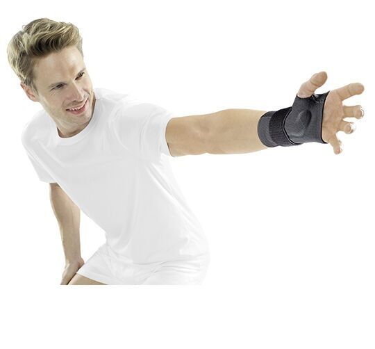 Person mit Handgelenkbandage am linken Arm. Bandage in Schwarz, bedeckt Handgelenk und Daumenansatz. Person trägt weißes T-Shirt.
