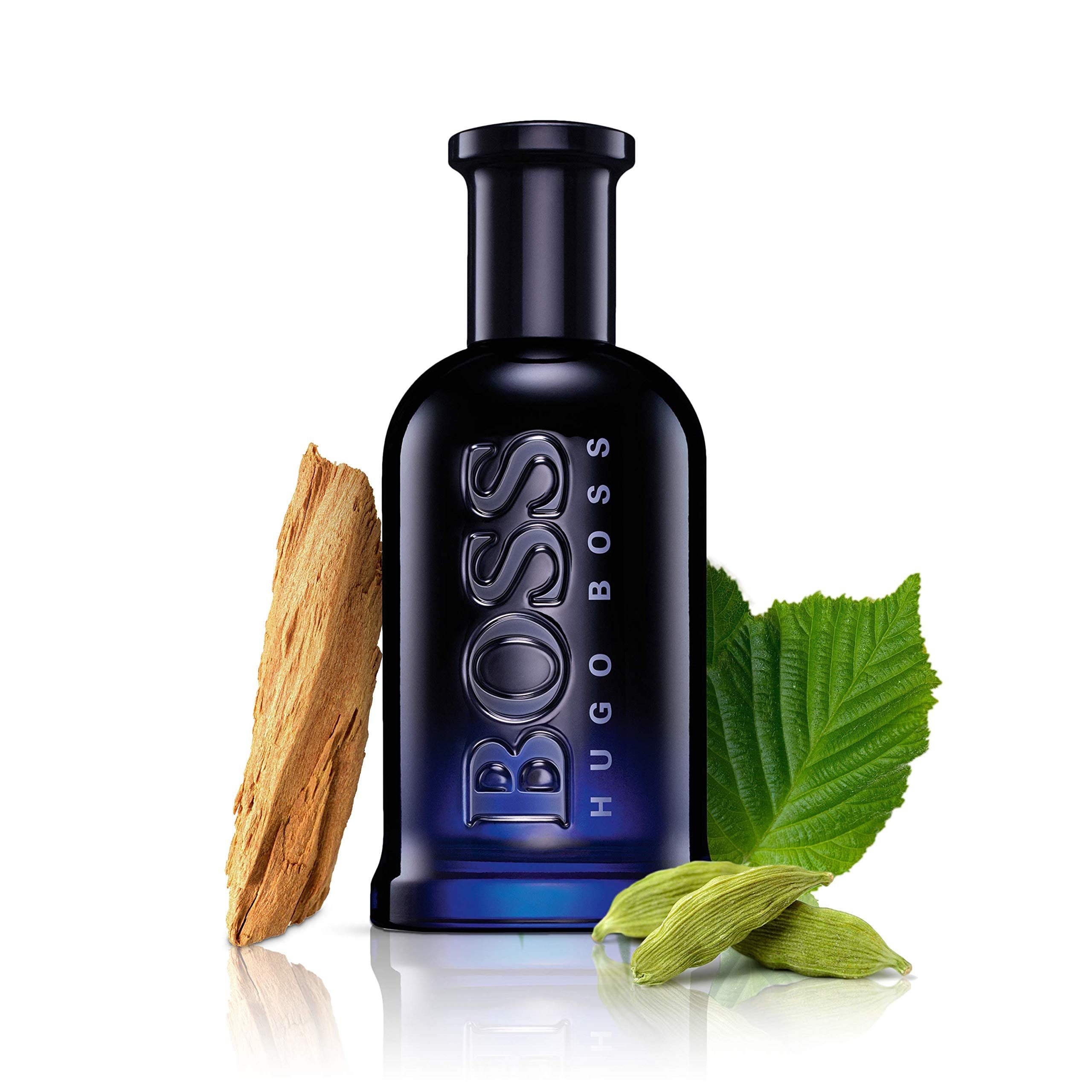 Dunkelblaue Glasflasche mit BOSS HUGO BOSS Schriftzug, umgeben von Holzstück, Blättern und Kardamom.