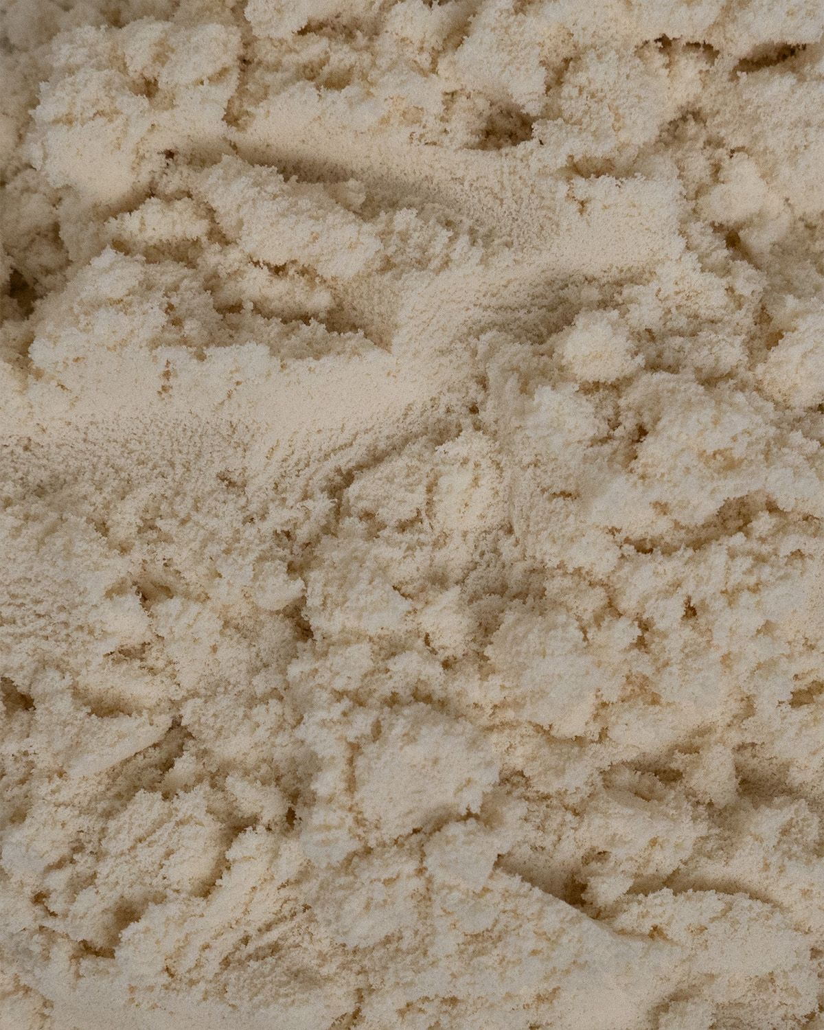 Nahaufnahme von Pulver. Die Textur ist körnig und hellbeige.