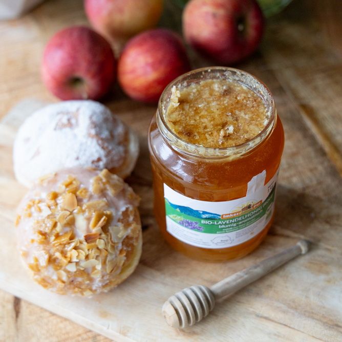 Glas Honig mit Etikett, Honigwabe und Honigheber. Aufschrift: BIO-Lavendelhonig (roh).