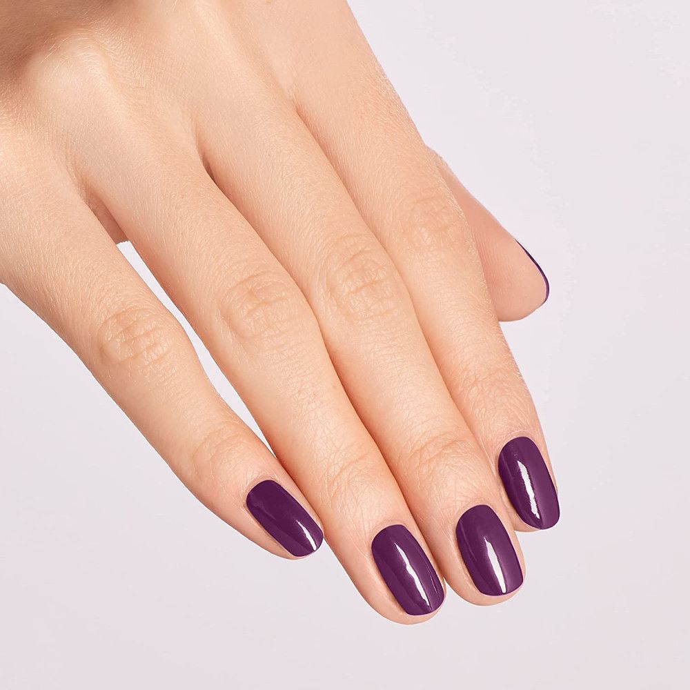 Hand mit lackierten Nägeln in dunklem Violett. Vier Nägel im Fokus. Glänzende Oberfläche.