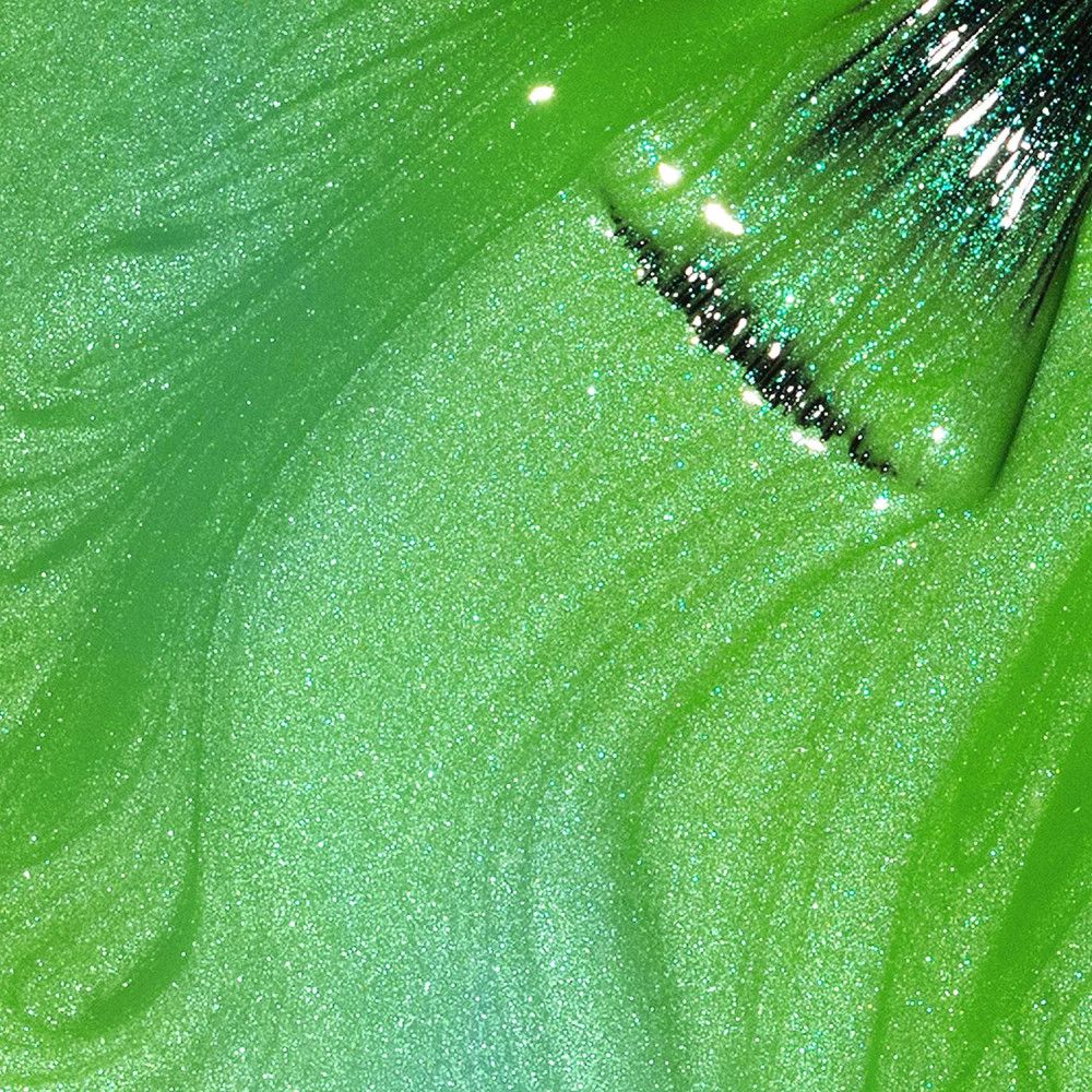 Grüner Nagellack mit Glitzer. Der Pinsel ist teilweise sichtbar.