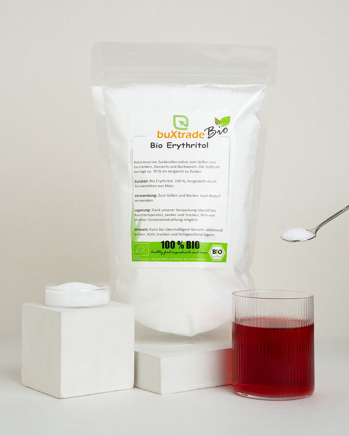 Standbodenbeutel mit Erythritol, daneben ein Glas Getränk und ein Löffel Erythritol.