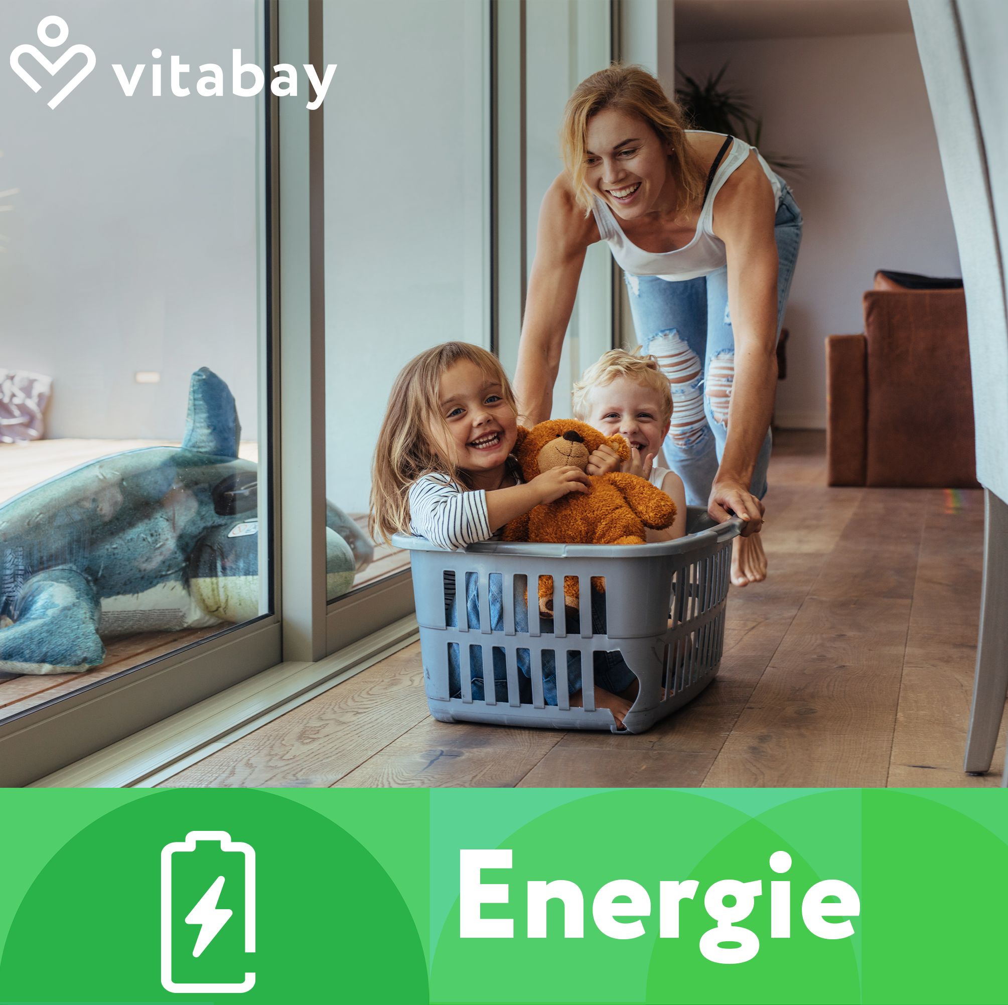Logo Vitabay. Text: Energie. Frau schiebt Kinder in Wäschekorb. Kinder lachen. Hintergrund: Fenster, Wohnraum.