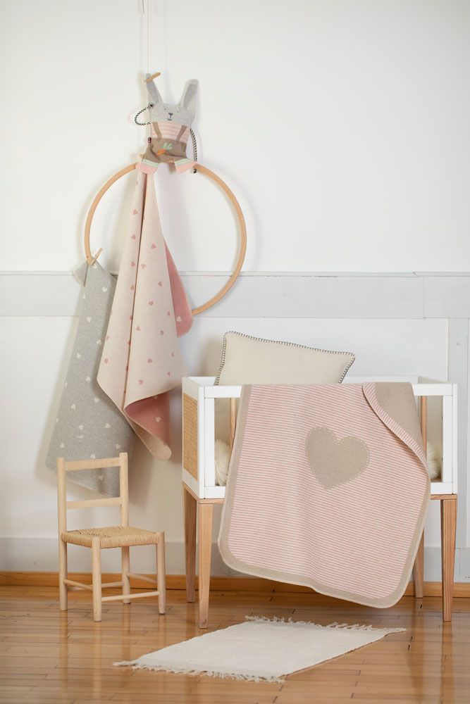 Babybett mit Decken, Kissen und Spielzeug. Eine Decke hat Streifen und ein Herz.