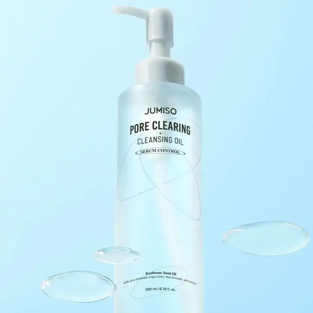 Klarflasche mit Pumpe. Aufschrift: JUMISO PORE CLEARING CLEANSING OIL. Serum Control. Wassertropfen im Hintergrund.