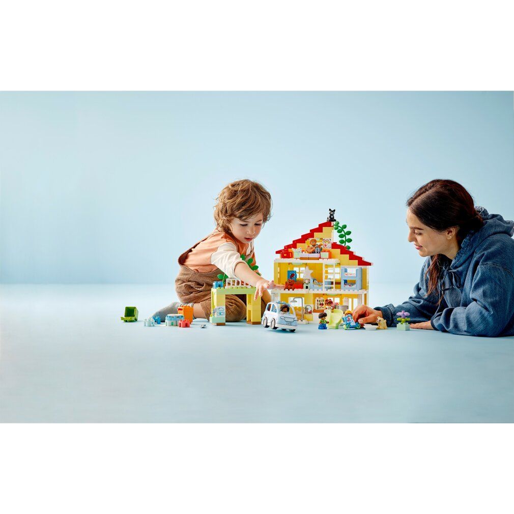 Kind und Erwachsene spielen mit LEGO Duplo 3-in-1-Familienhaus. Gelbes Haus, Figuren, Auto, Rutsche und Zubehör.