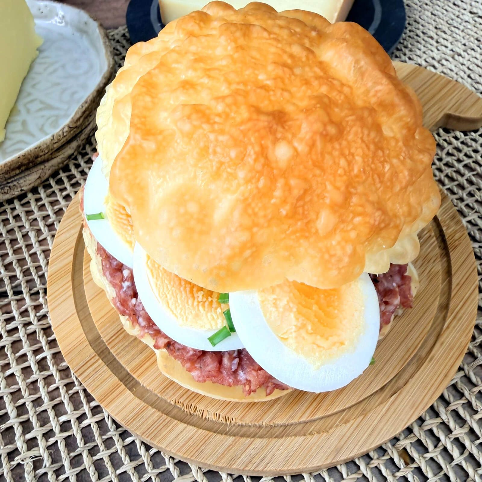 Ein Locawo Dreikäsehoch Brötchen belegt mit Wurst und Ei, Nahaufnahme.