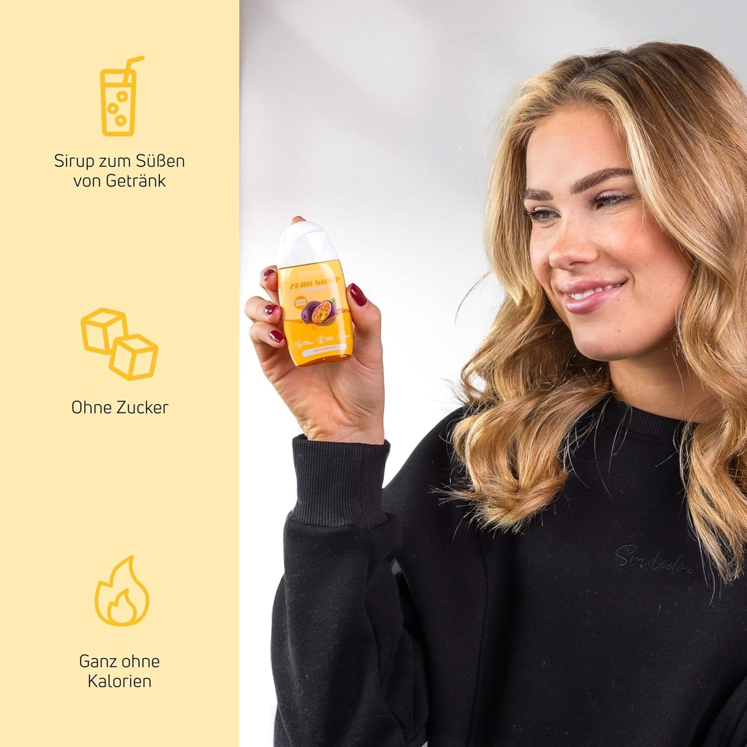 Frau hält eine Flasche Sirup. Auf der Flasche steht: Ohne Zucker, ganz ohne Kalorien. Auf dem Etikett ist eine Passionsfrucht abgebildet.