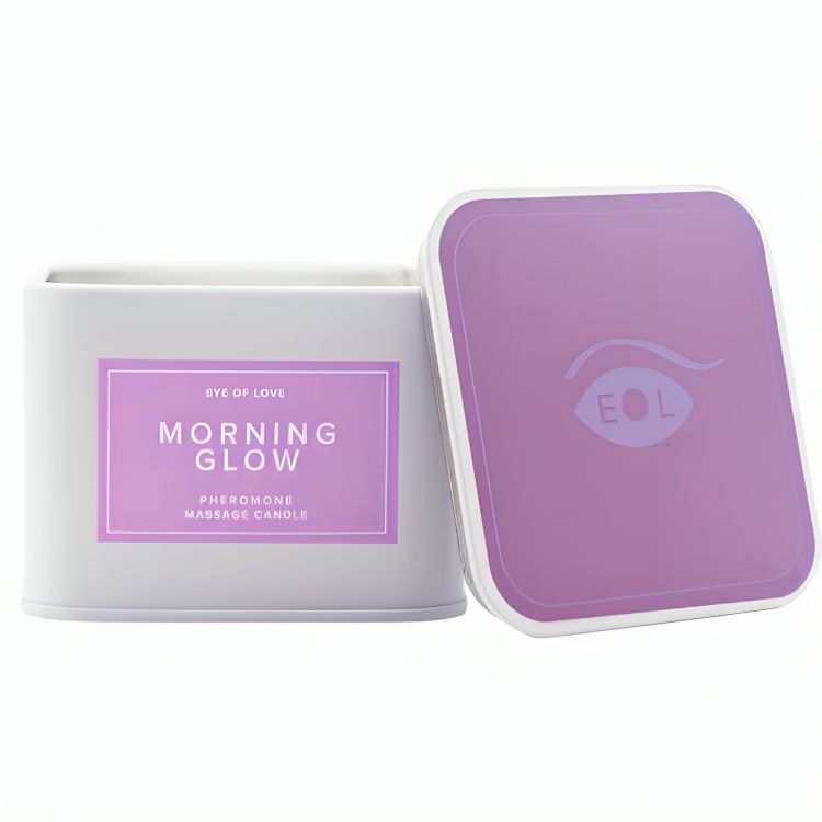 Weißer, quadratischer Behälter mit lila Deckel. Aufschrift: Eye of Love, Morning Glow, Pheromone Massage Candle.