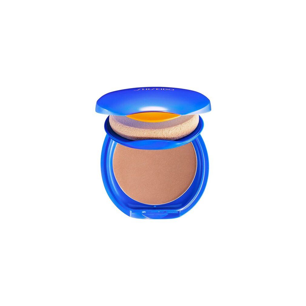 Blauer Kompakt-Make-up-Behälter mit geöffnetem Deckel. Enthält einen Schwamm und einen braunen Puder. Oben steht "Shiseido".