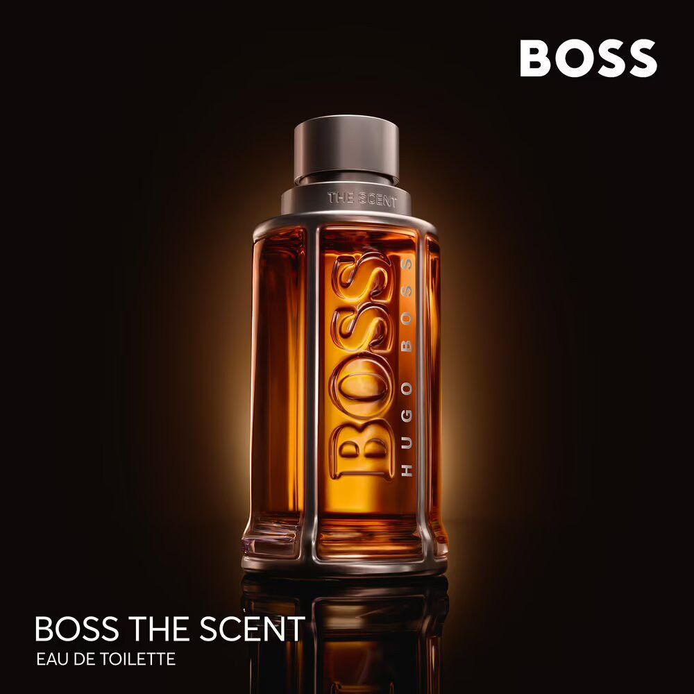 Hugo Boss The Scent Flakon. Glasflakon mit silbernem Deckel und Metallrahmen. Aufschrift BOSS, THE SCENT und Eau de Toilette.
