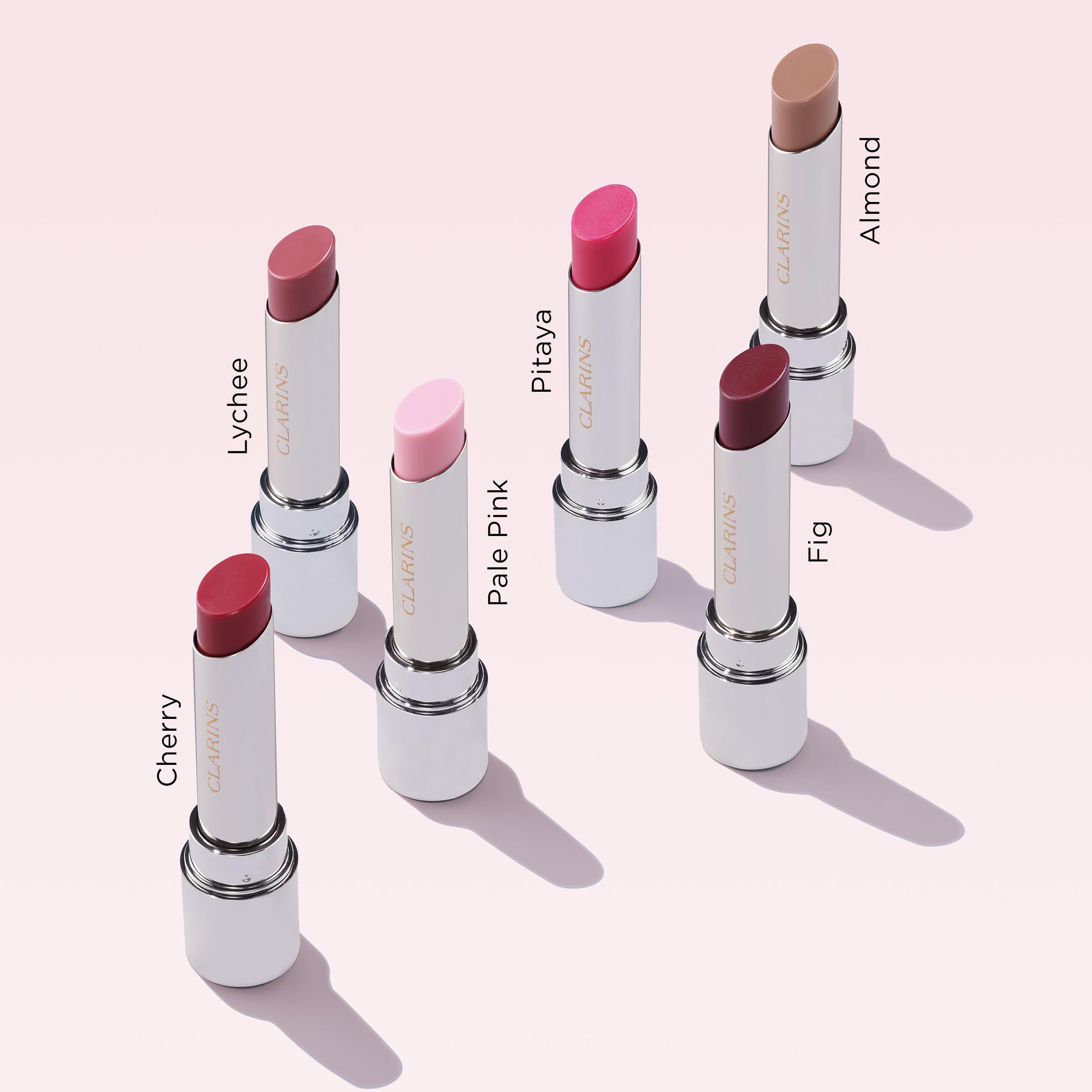 Sechs Lippenbalsam-Stifte in verschiedenen Farben. Weißer Stift, goldfarbene Basis. Aufschrift: CLARINS. Farbbezeichnungen.