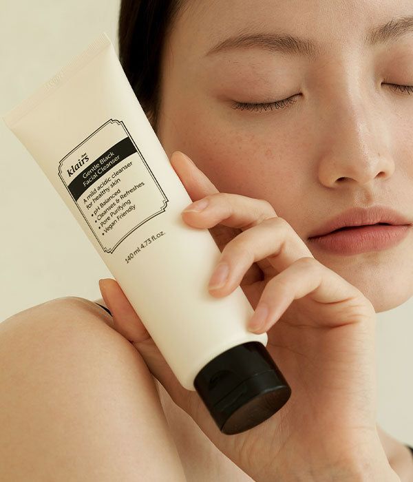 Frau hält eine Tube. Aufschrift: Gentle Black Facial Cleanser. Vegan. Hautpflegeprodukt.