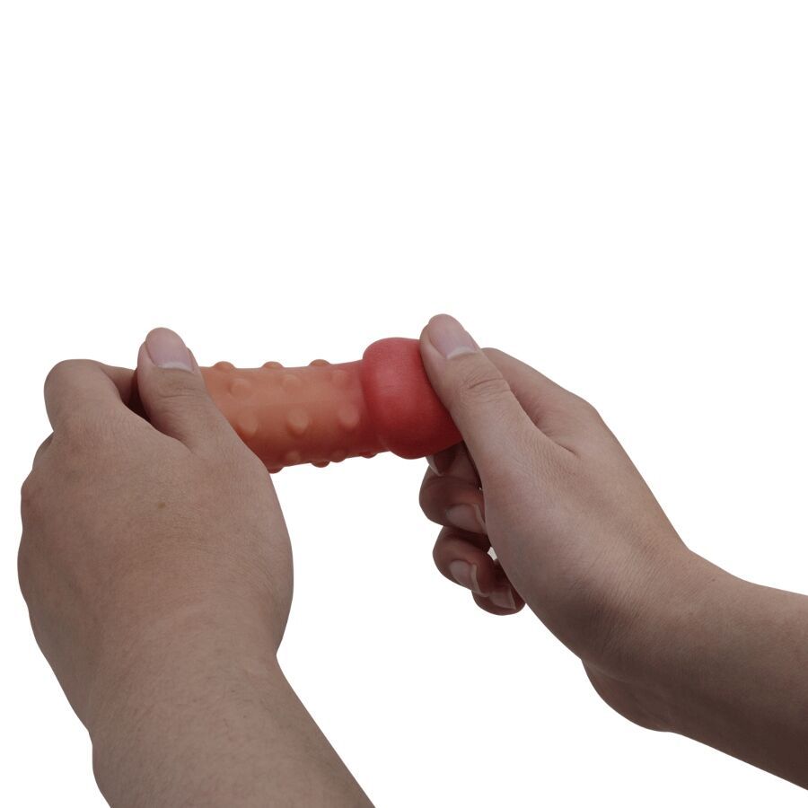 Hände halten einen braunen Penisverstärker mit roter Spitze und Noppen.