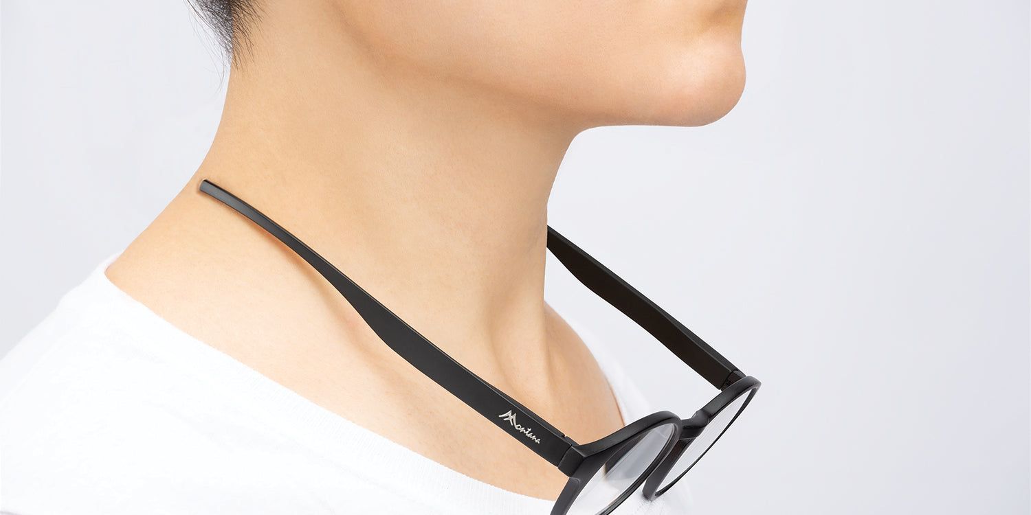 Brille mit schwarzen Bügeln um den Hals einer Person. Der Markenname ist auf dem Bügel zu sehen.