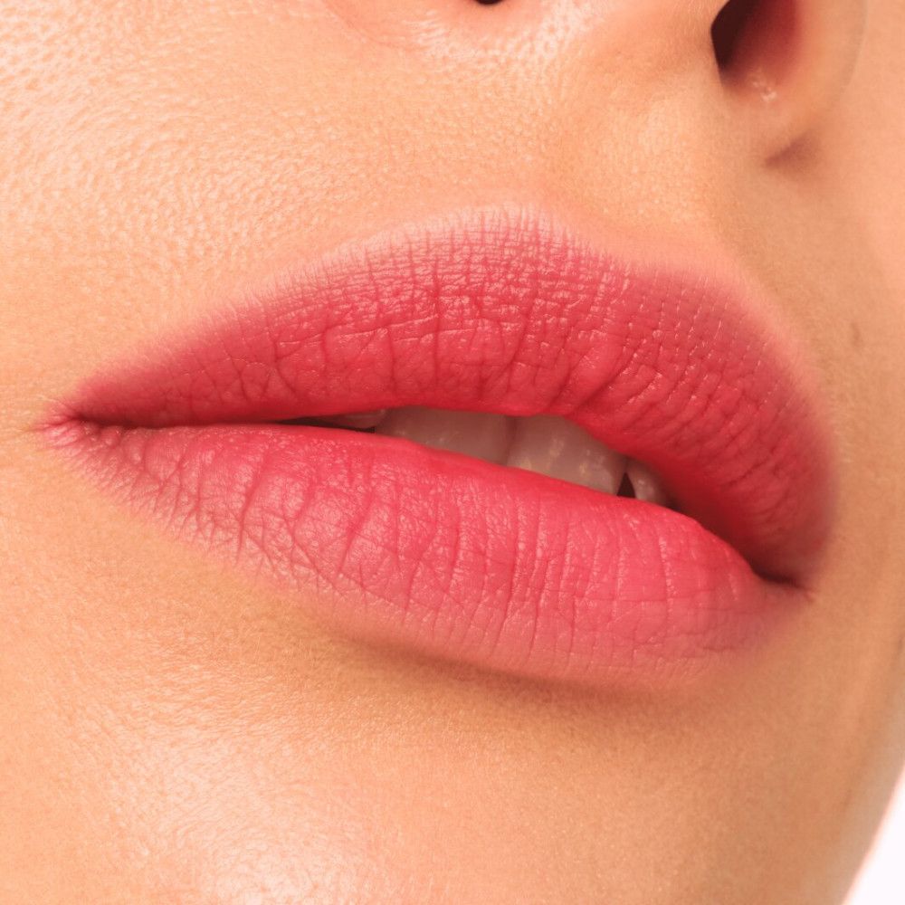 Nahaufnahme von Lippen, die mit einem matten, rosafarbenen Lippenstift bemalt sind.