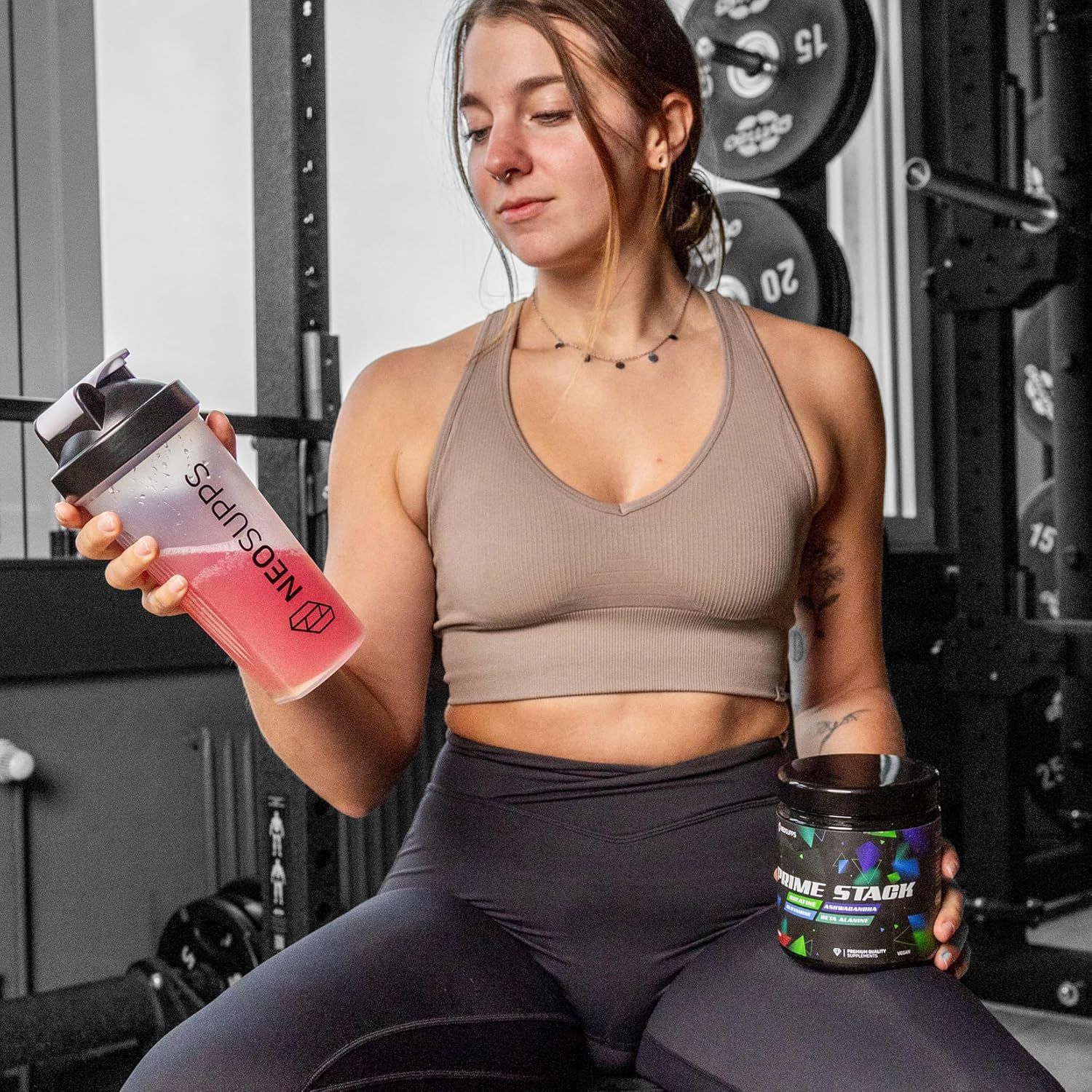Frau mit Shaker und Dose Prime Stack. Shaker mit rosa Flüssigkeit. Dose mit Aufschrift Prime Stack, Creatine, Ashwagandha, Beta Alanin.
