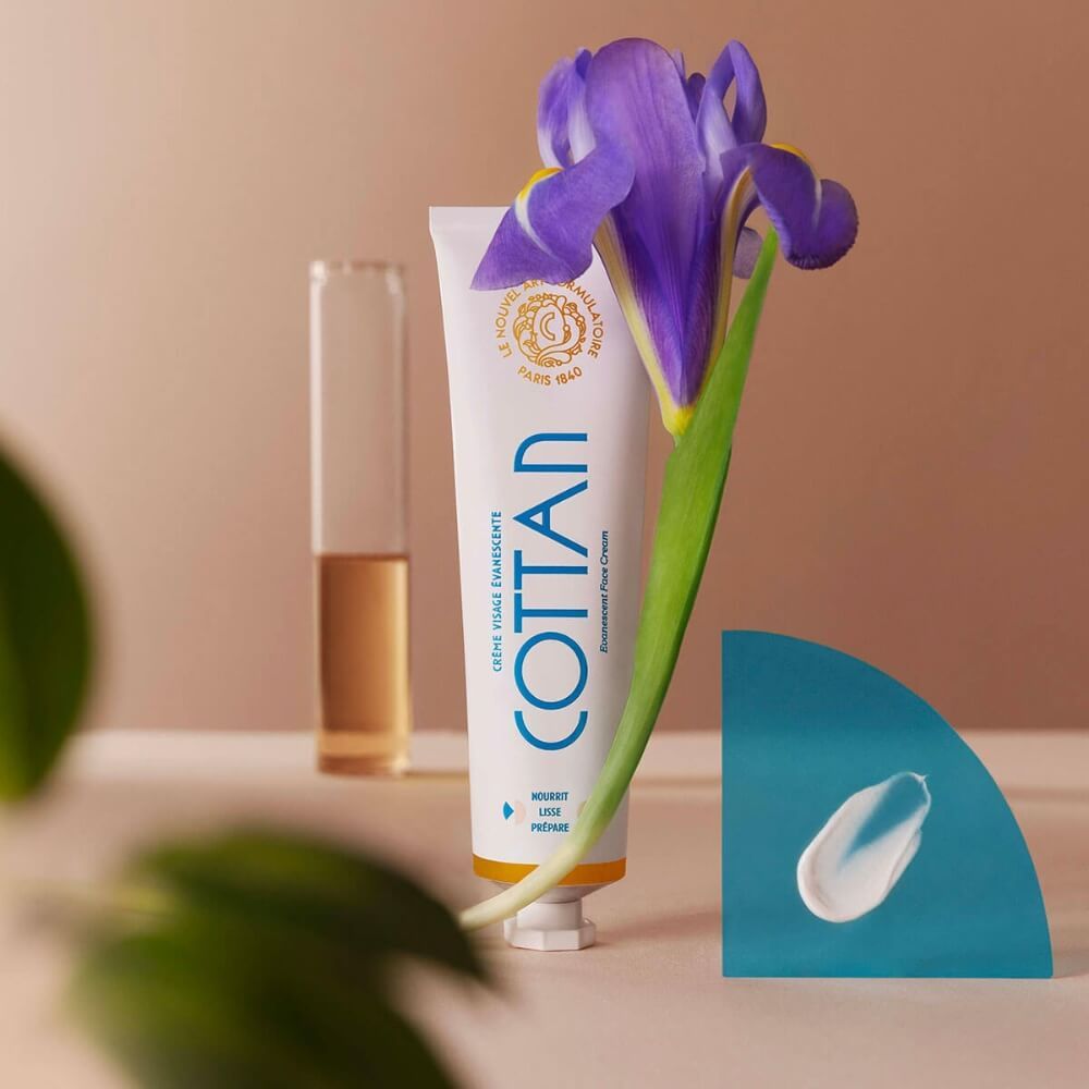 COTAN Creme-Tube. Irisblüte und Creme-Klecks. Hintergrund mit Flüssigkeit.