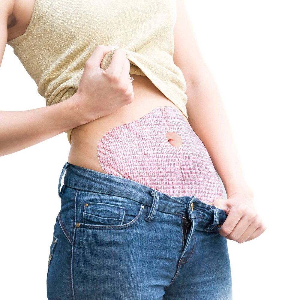 Person trägt ein Fitness-Schlankheits-Pflaster auf dem Bauch. Das Pflaster ist rosa und hat ein Loch.