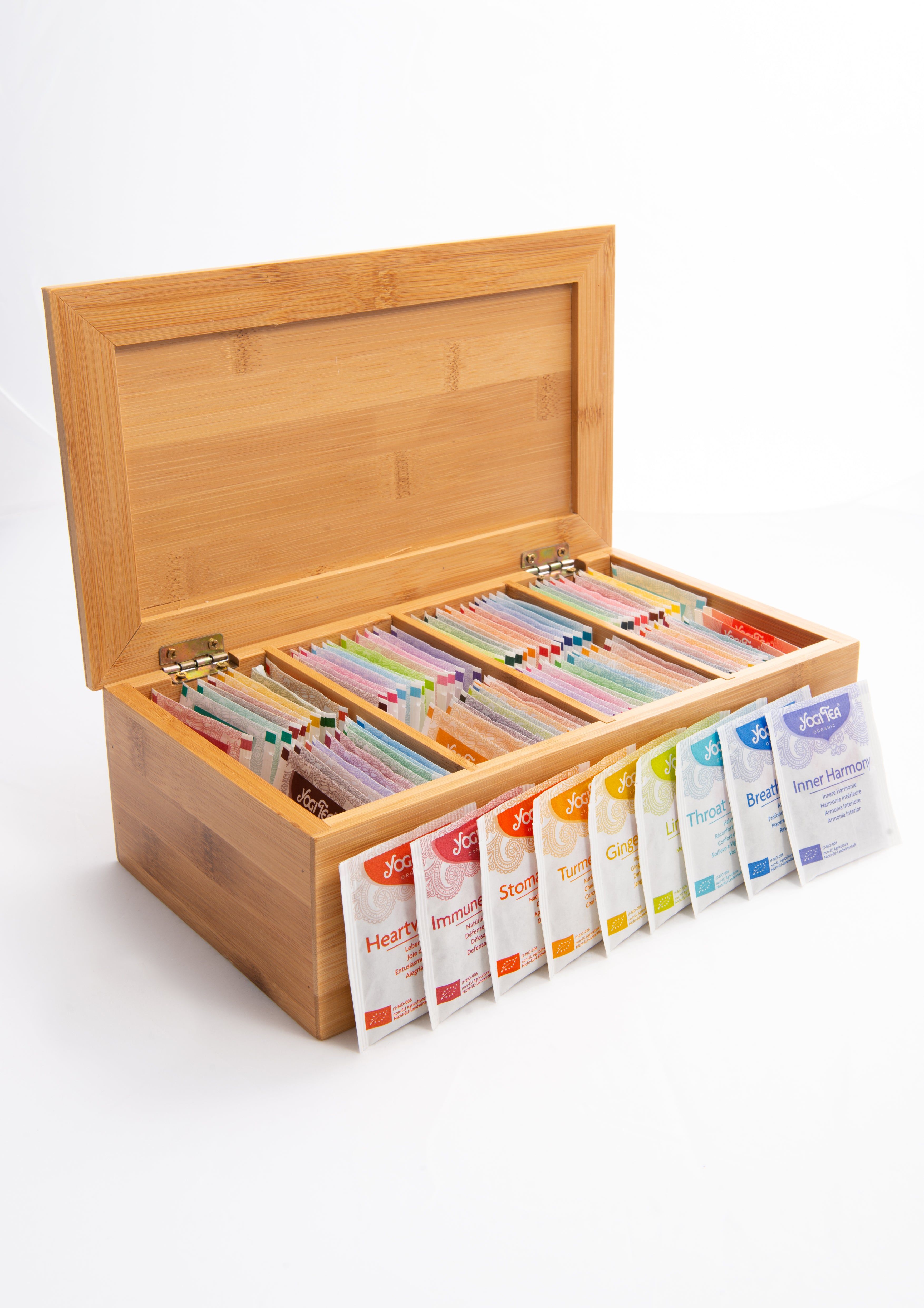 Holzbox mit Deckel, gefüllt mit Teebeuteln in verschiedenen Farben. Einige Teebeutel sind aus der Box genommen und aufgereiht.