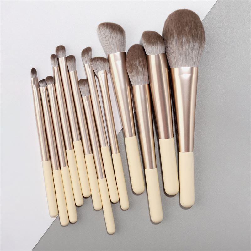 Make-up Pinsel-Set. 12 Pinsel mit cremefarbenen Griffen, silbernen Hülsen und verschiedenen Pinselköpfen.