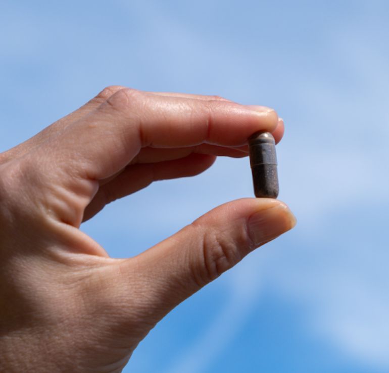 Hand hält eine einzelne Aavalabs Himalaya Shilajit Kapsel.