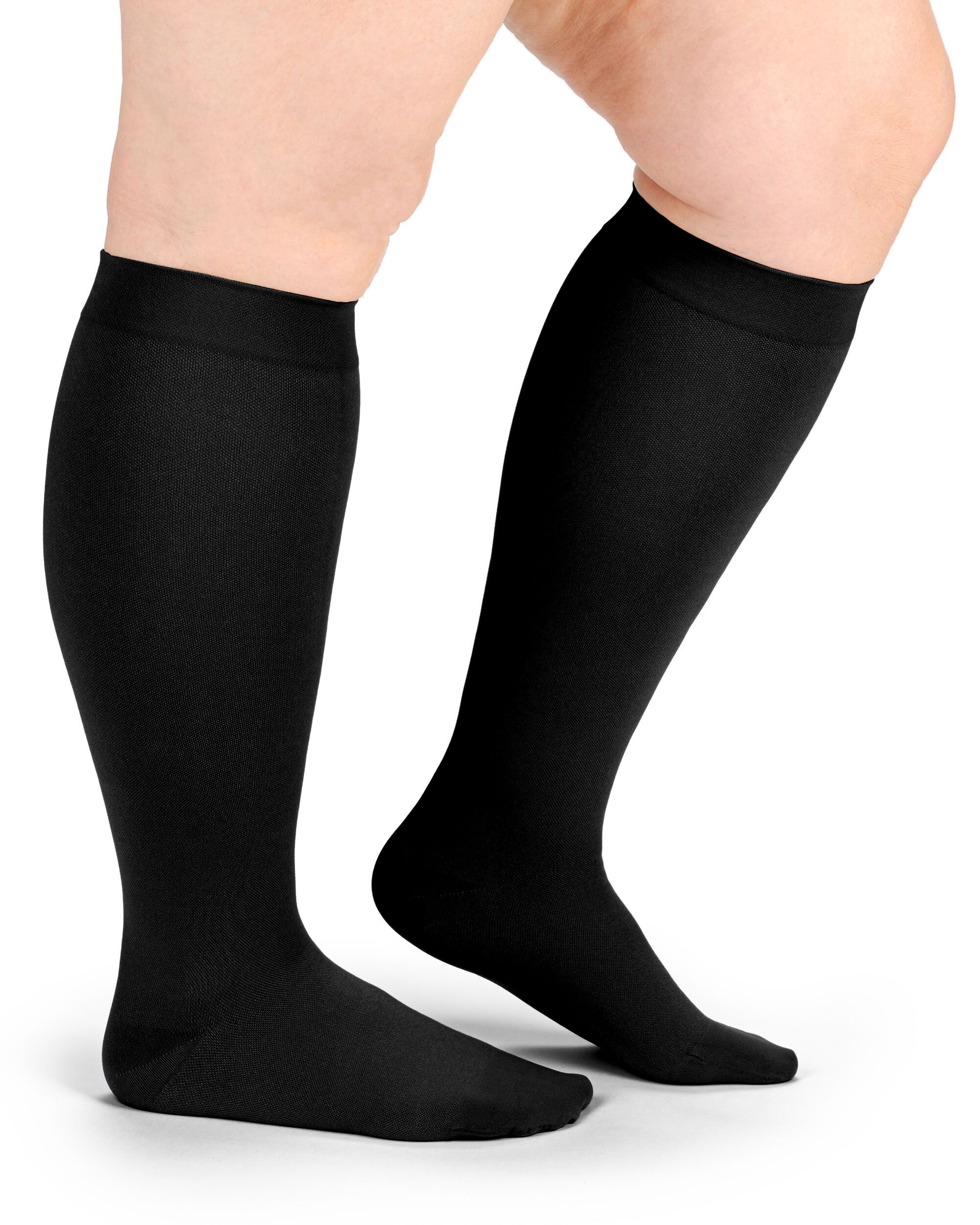 Schwarze Kompressionsstrümpfe am Bein einer Person. Blick von der Seite, die Strümpfe reichen bis zum Knie.