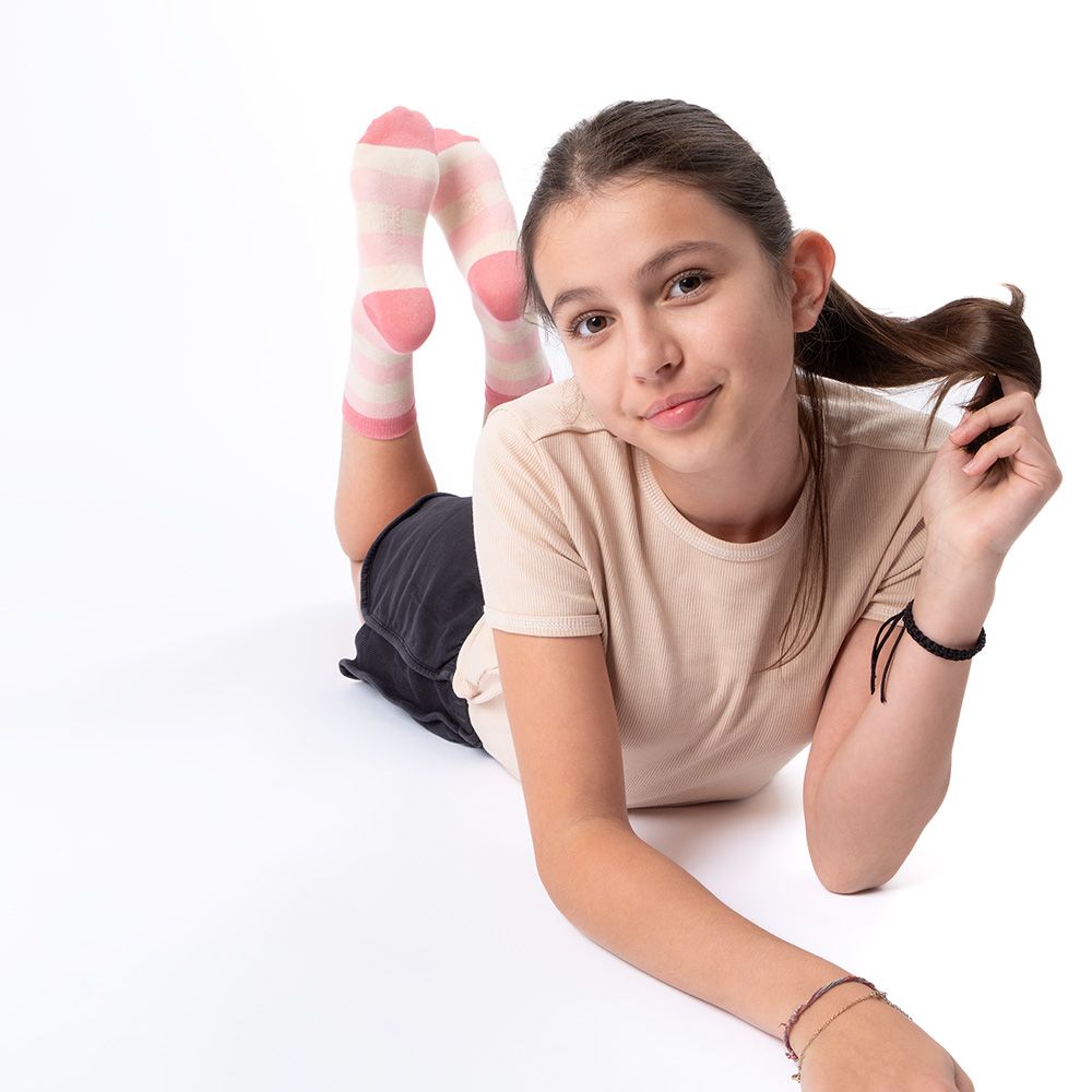 Mädchen liegt, trägt rosa gestreifte Socken. Rosa und weiße Streifen. Mädchen liegt auf dem Bauch.