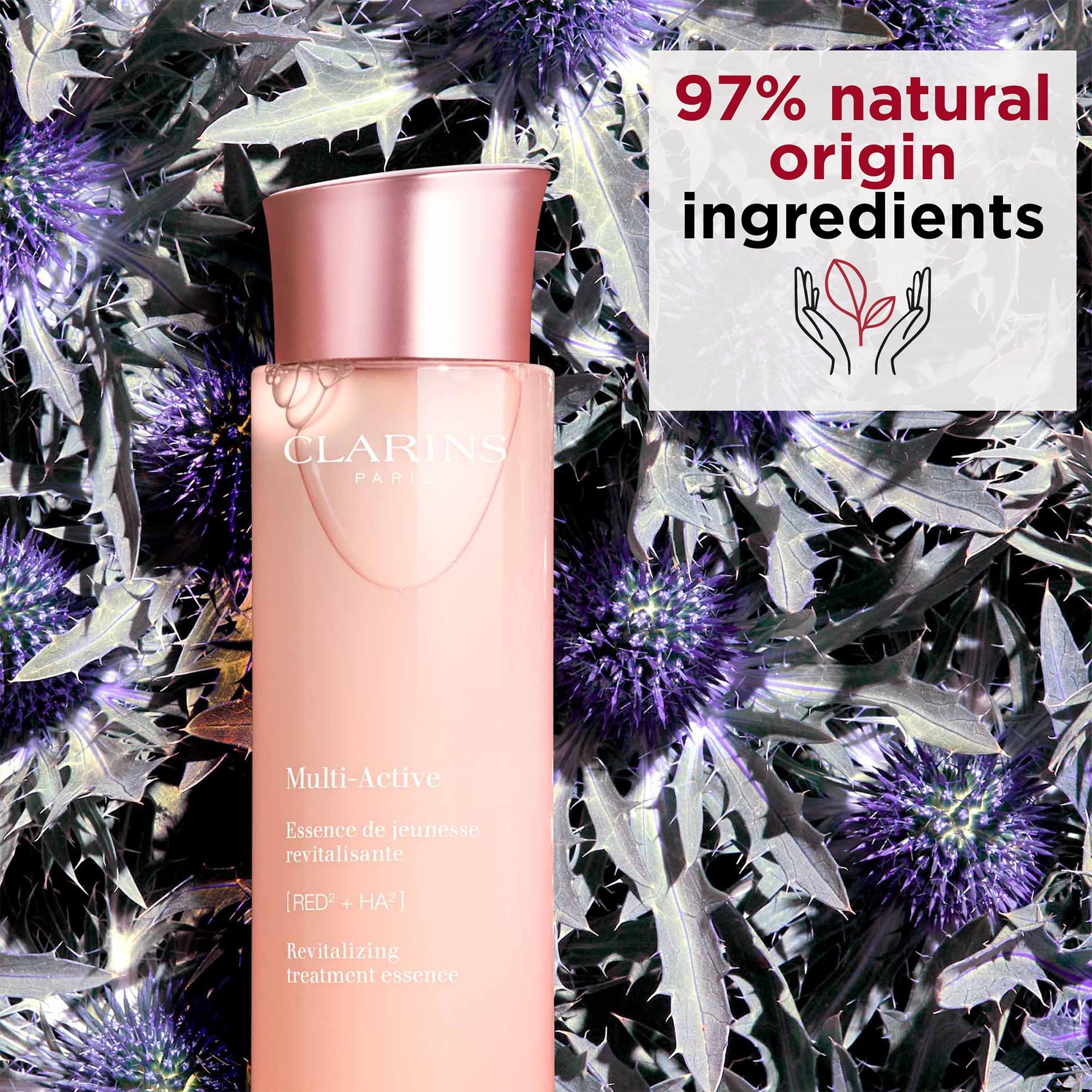 Clarins Multi-Active Essenz. Rosa Flasche mit silbernem Deckel. Text: Multi-Active, Revitalizing treatment essence. Hintergrund: Blumen.