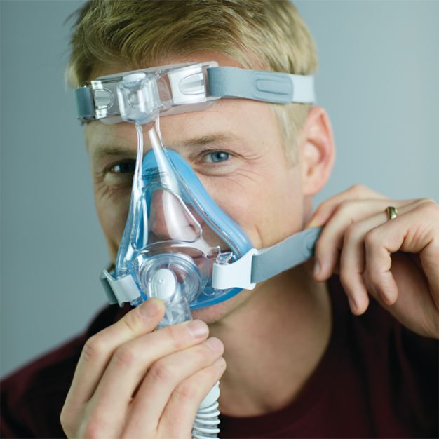 Mann mit Philips CPAP Maske Amara SE Gel Full: Mund-Nasenmaske wird angelegt.