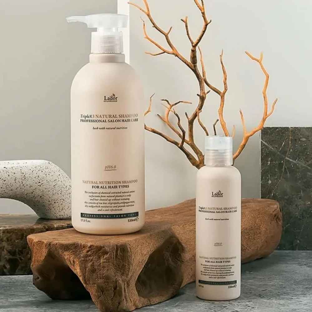 Zwei Flaschen TripleX3 Natural Shampoo, professionelle Haarpflege, auf Holz und Stein arrangiert.
