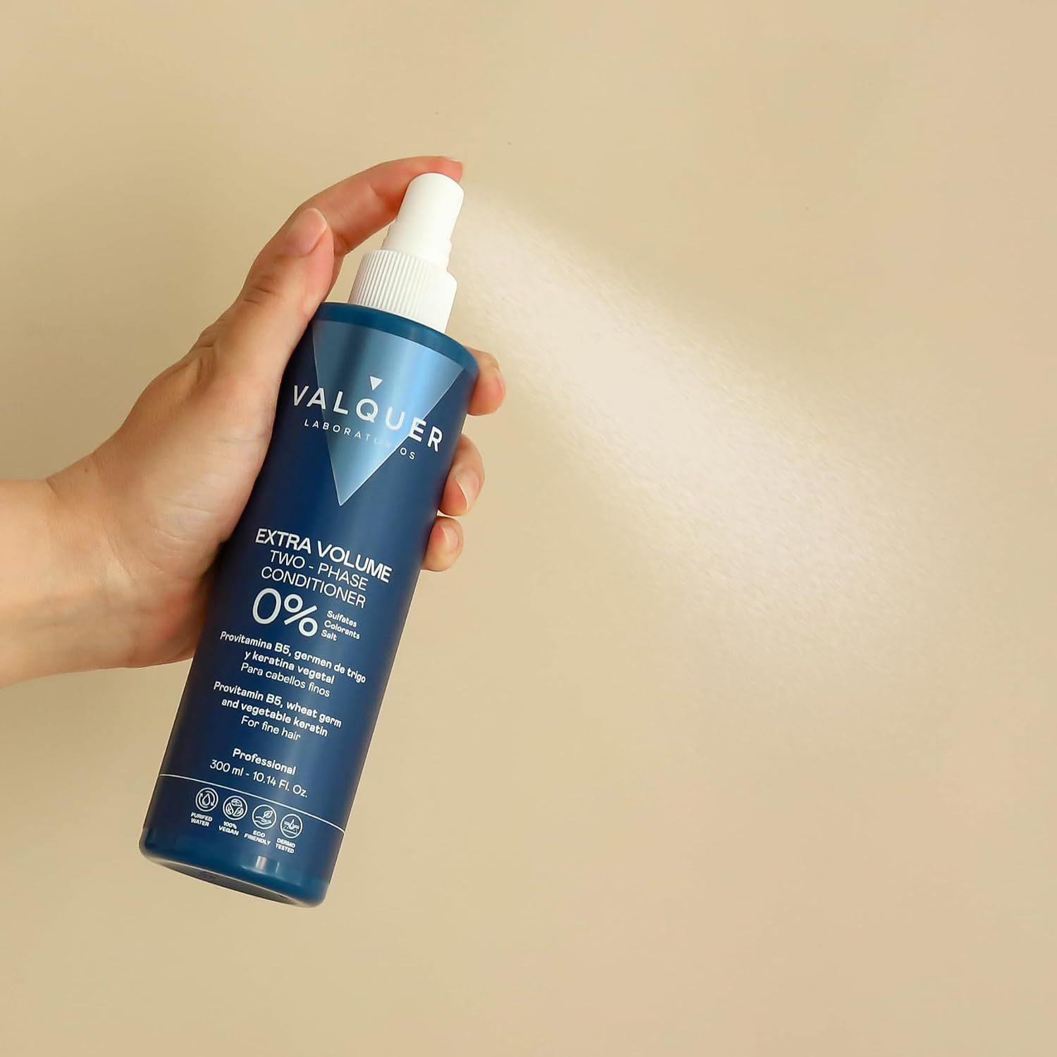 Hand sprüht Valquer Extra Volume Two-Phase Conditioner aus einer blauen Flasche.