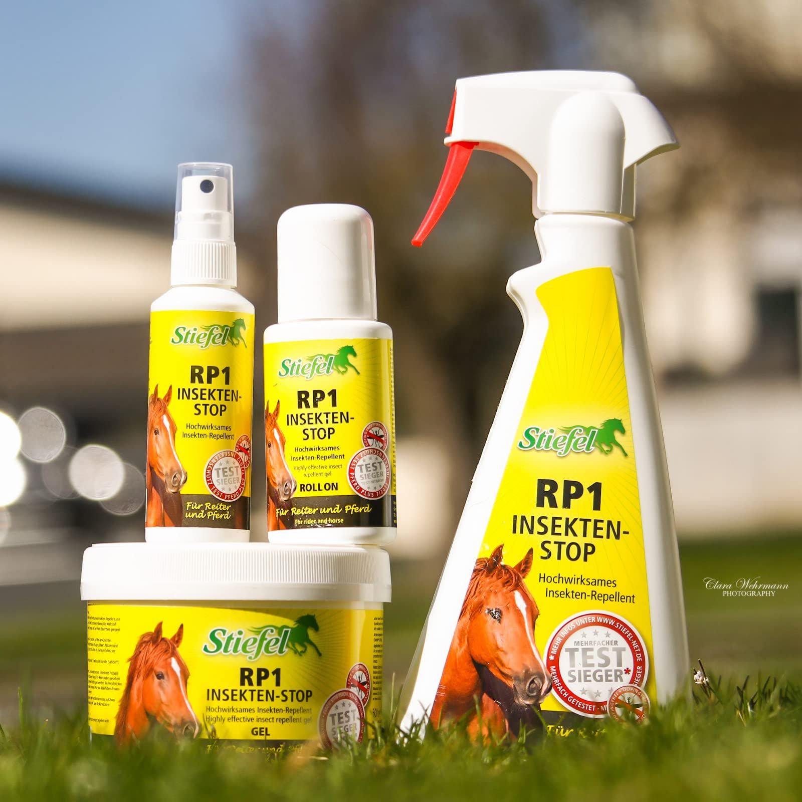 Verschiedene Behälter von Stiefel Insekten-Stop auf Gras. Sprays, Flaschen und Creme. Gelbe Etiketten mit Text.