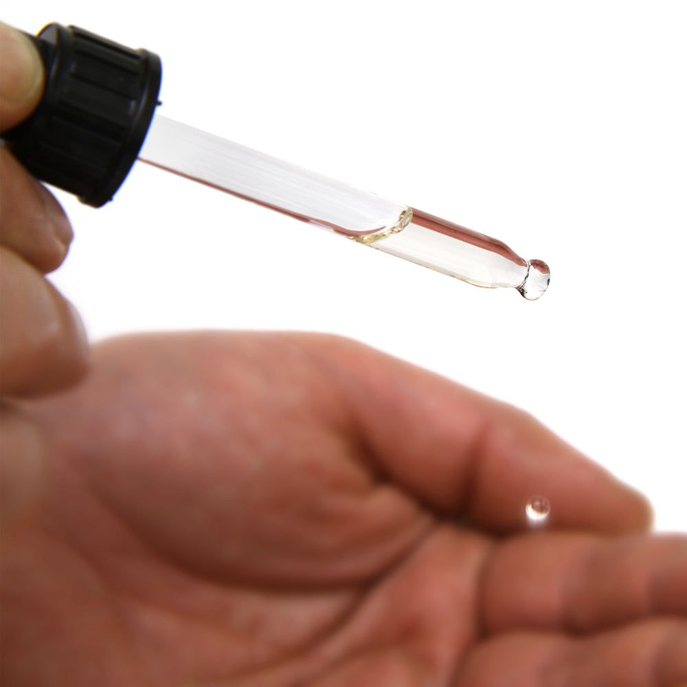 Hand mit Pipette, die einen Tropfen Monsieur BARBIER Bio-Trockenöl abgibt.