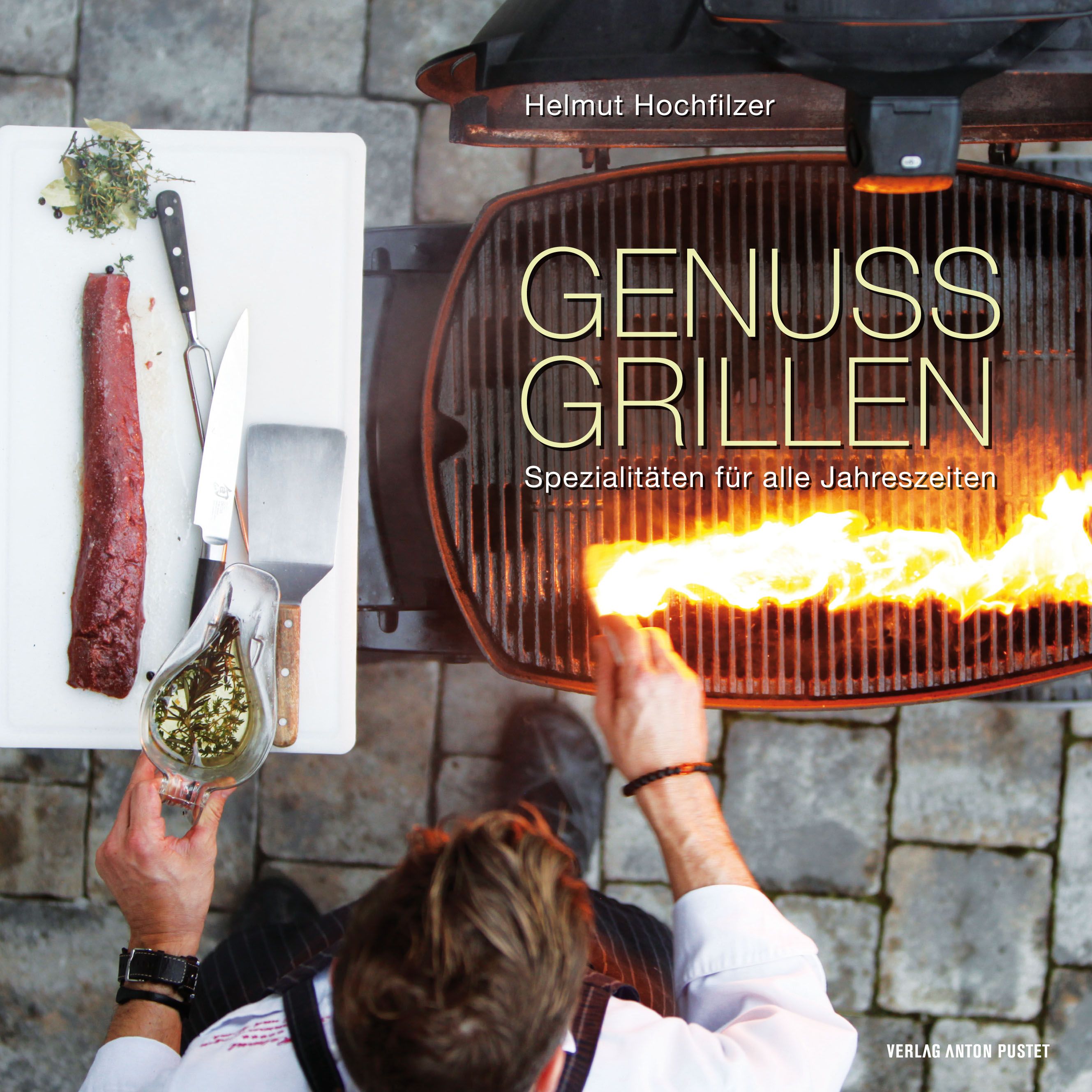 Buchcover mit Titel GENUSS GRILLEN. Autor Helmut Hochfilzer. Auf einem Grill wird Feuer entfacht. Auf einem Brett liegen Fleisch und Kräuter.