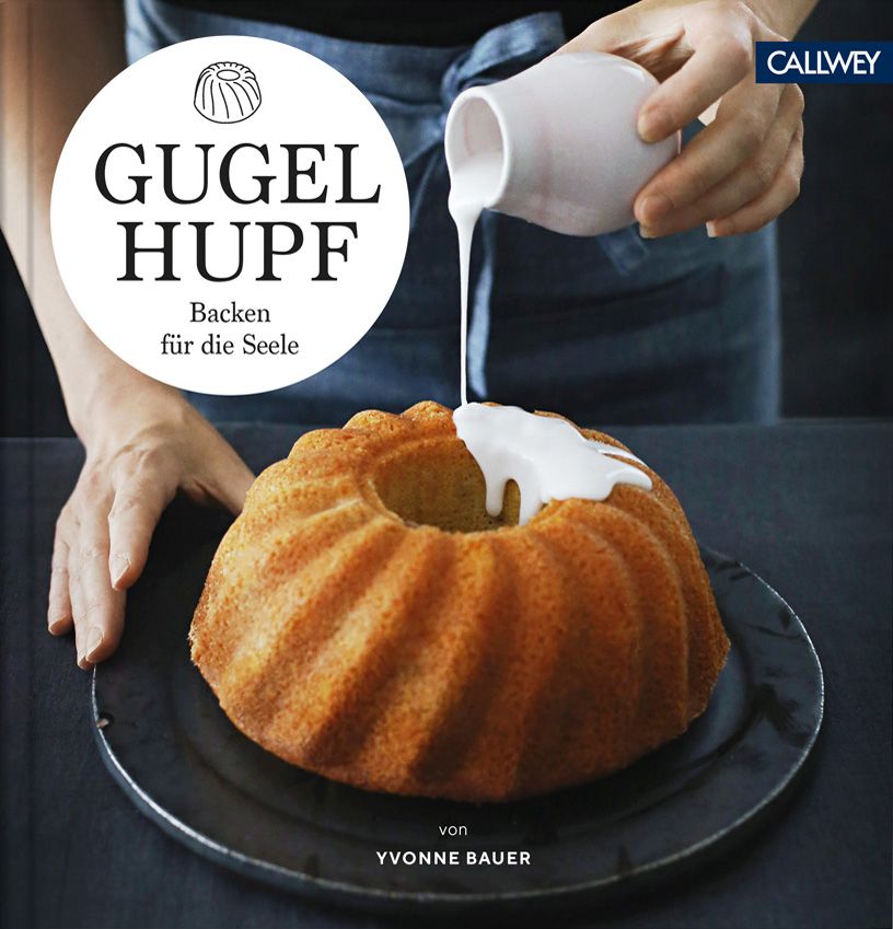 Gugelhupf-Buch mit Titel und Autor. Kuchen wird mit weißer Glasur übergossen. Auf schwarzem Teller, von Yvonne Bauer.