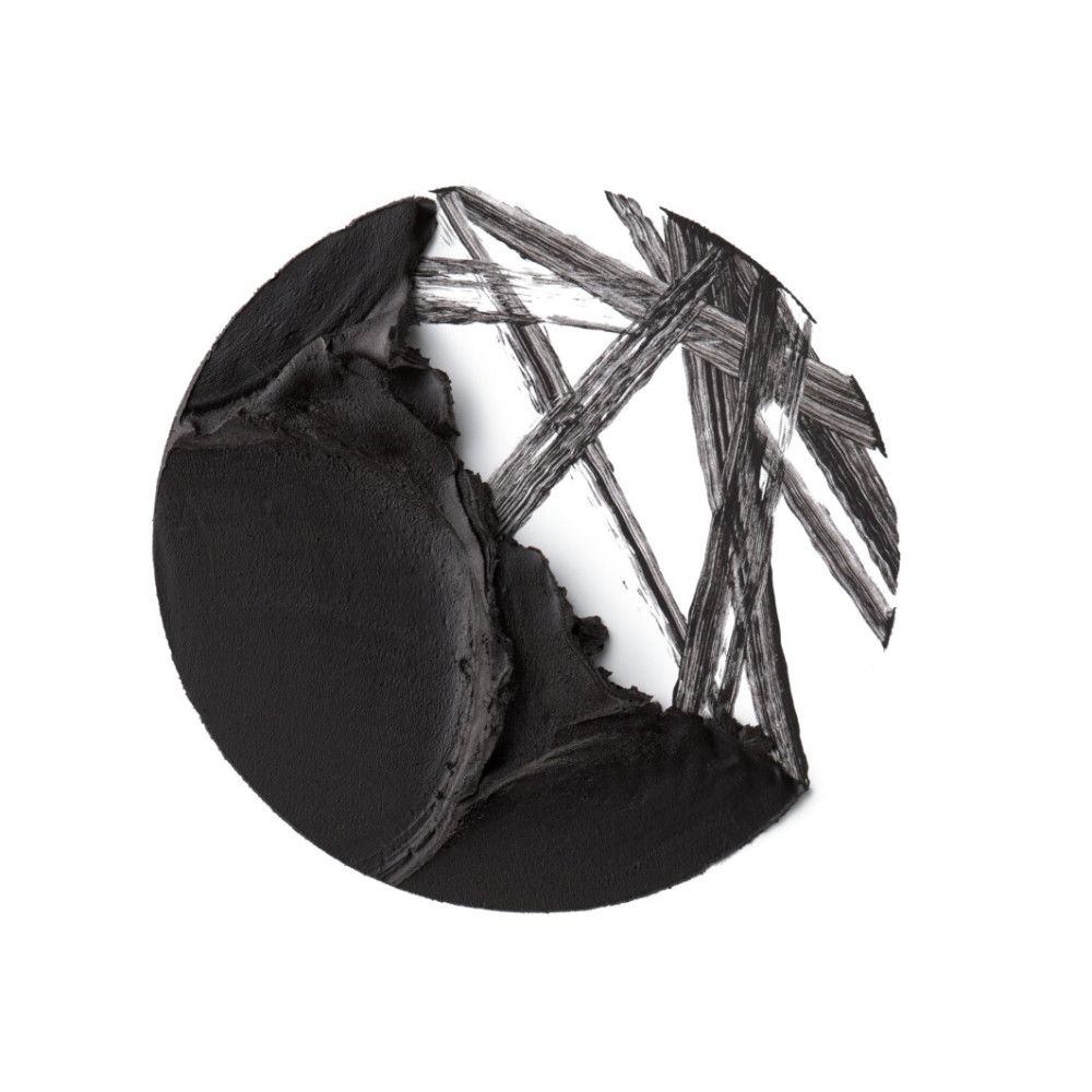 Kreisförmige Nahaufnahme von schwarzem Eyeliner-Gel. Einige Striche sind auf weißem Hintergrund zu sehen.