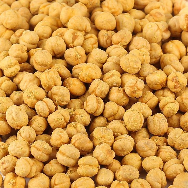 Nahaufnahme von gelben Kichererbsen mit Salz. Einzelne Hülsenfrüchte, unscharfer Hintergrund.