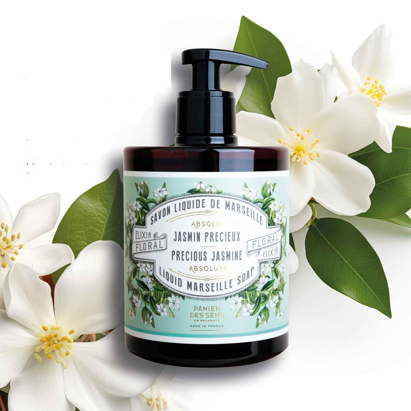 Flüssigseife in brauner Pumpflasche, umgeben von Jasminblüten und Blättern.