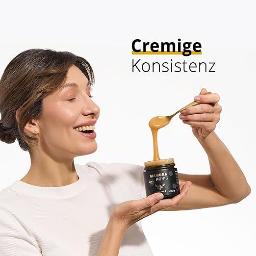 Frau hält Honigglas und Löffel. Text: Cremige Konsistenz. Aufschrift: MANUKA HONIG, 250g e.