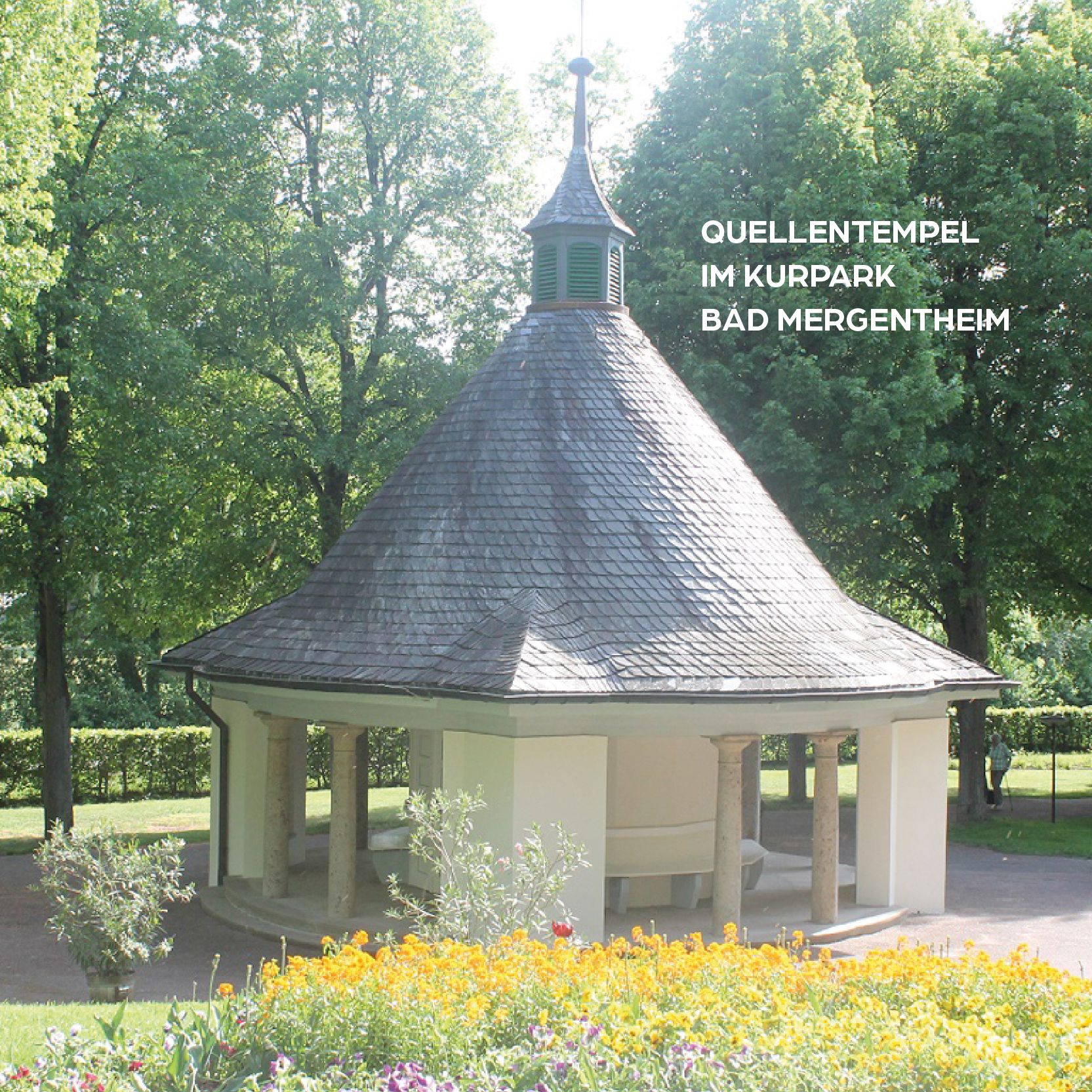Pavillon im Kurpark Bad Mergentheim. Grünes Dach, weisse Säulen, gelbe Blumen.