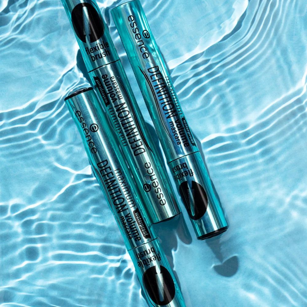 Drei türkisfarbene Mascaratuben im Wasser. Aufschrift: maximum DEFINITION volume mascara, flexible brush. Marke: essence. Wasser mit Reflexionen.